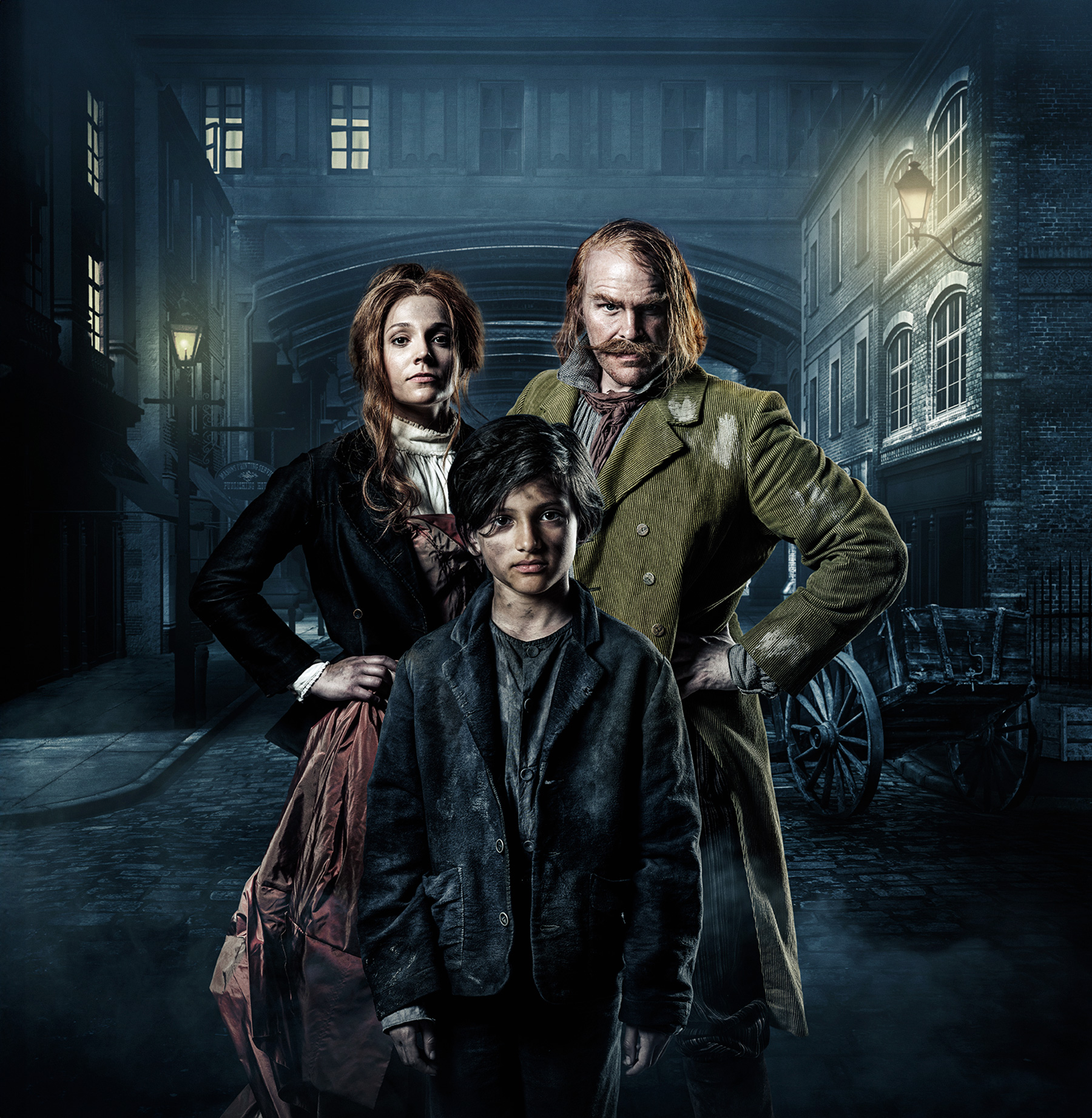 Three individuals stand on a dark, foggy street within a historical setting. Their attire reflects the style of the 19th century. On the left, a woman dons a dress; to the right, a man is dressed in a suit, with a child in more casual, relaxed clothing in the middle. The backdrop reveals a dim, mist-filled lane flanked by historical buildings and street lamps casting a faint glow. A horse and carriage are further discernable in the background, indicating the scene represents a previous era. The atmosphere is somber and mystifying, amplified by the dim light and the shadows enveloping the figures and structures.
